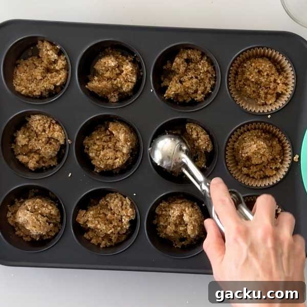Adding the cheesecake crust to the muffin cups.