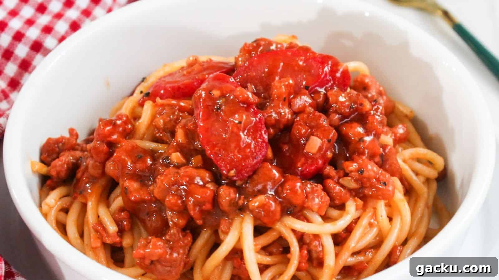 30 One-Pan Skillet Meals for Quick Cleanup and Big Flavor 26 A bowl of spaghetti topped with a rich meat sauce placed on a red and white checkered tablecloth.