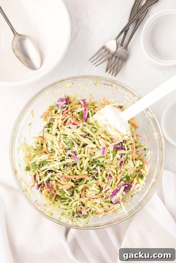 A bowl of healthy broccoli slaw with a spatula. 