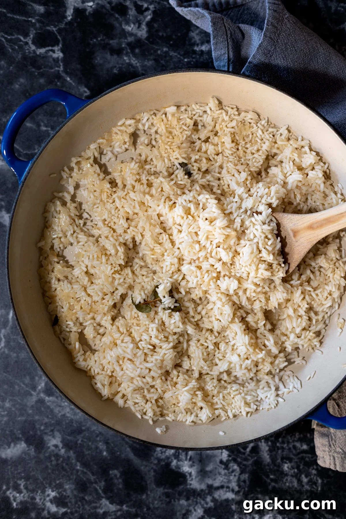 Simple Rice Pilaf Recipe: Fluffy, Flavorful Rice Pilaf in 30 Minutes 2 Skillet on a counter with rice pilaf, spoon in skillet.