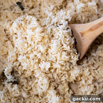 Simple Rice Pilaf Recipe: Fluffy, Flavorful Rice Pilaf in 30 Minutes 11 Closeup of rice pilaf with wooden spoon.
