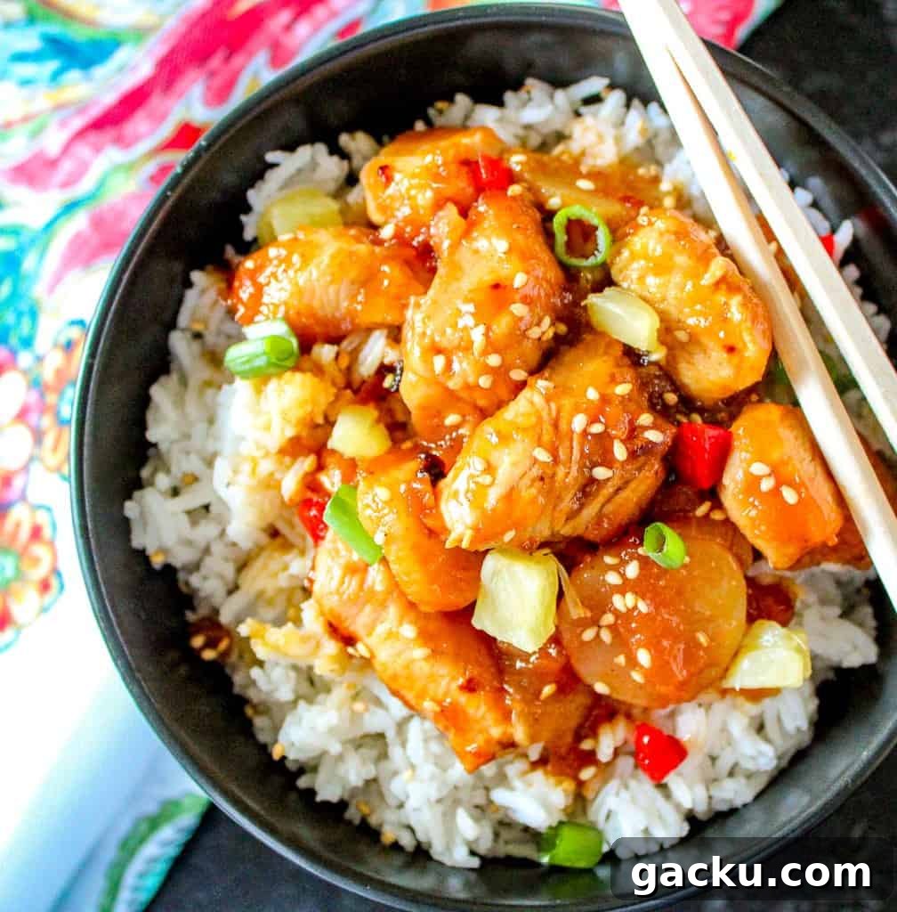 Sweet and sour shrimp on rice in black bowl.