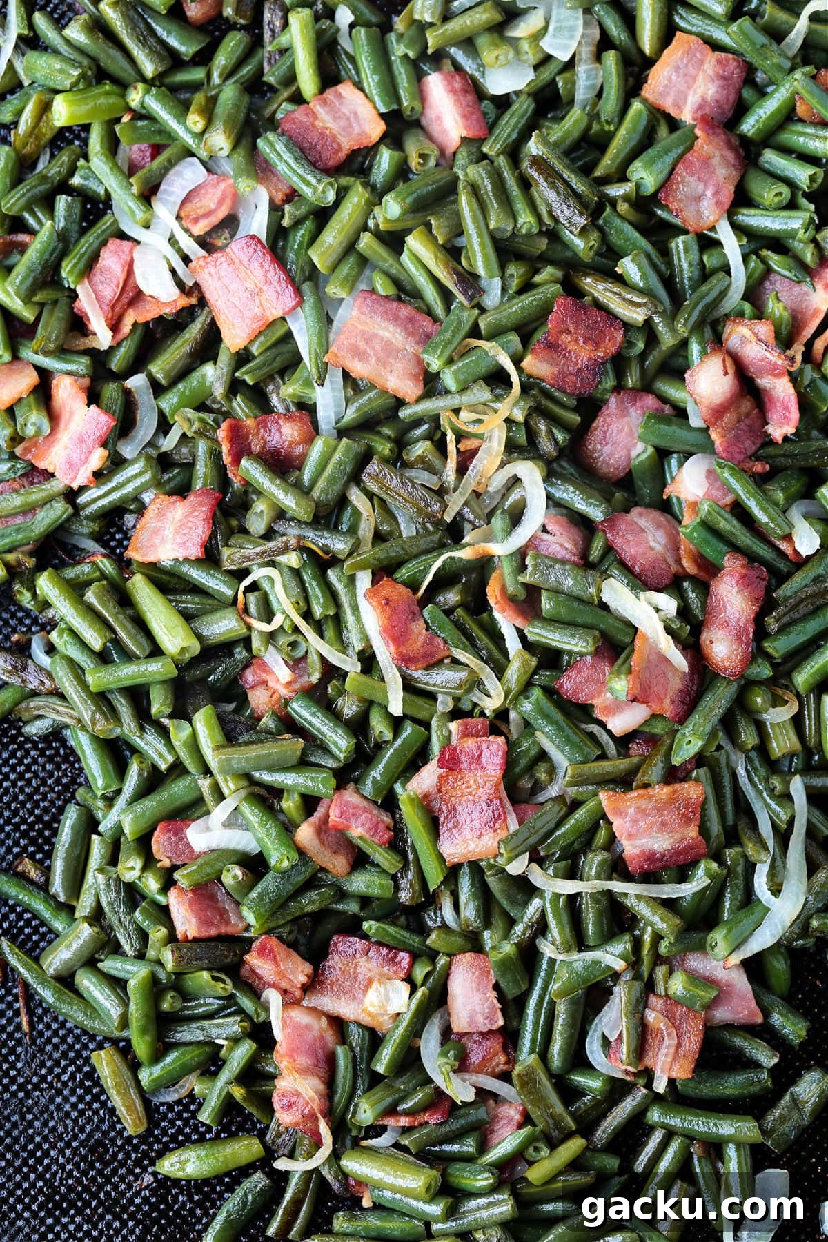 Cook: Place the sheet pan in the oven and cook for 20 minutes, toss and cook for another 20 minutes until the onions are soft and the green beans have color. green beans with bacon and onions on a sheet pan