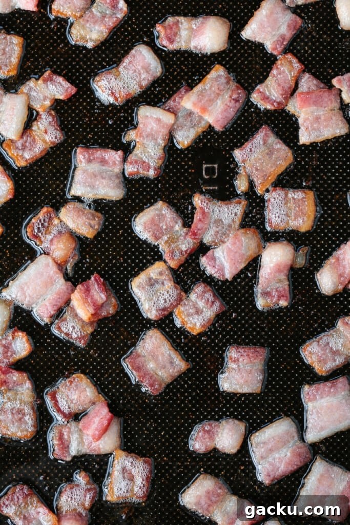 These Green Beans with Bacon are an easy to make, delicious vegetable side dish! Bacon and onions flavor the green beans while they cook! cooked diced bacon on a sheet pan
