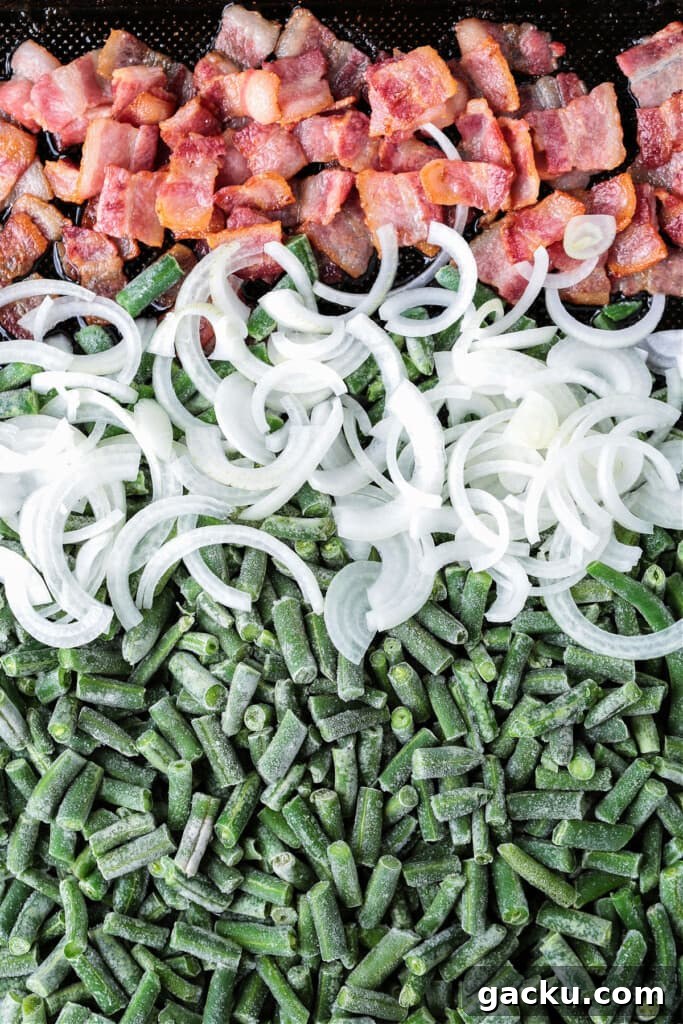 These Green Beans with Bacon are an easy to make, delicious vegetable side dish! Bacon and onions flavor the green beans while they cook! bacon, onions and frozen green beans on a sheet pan