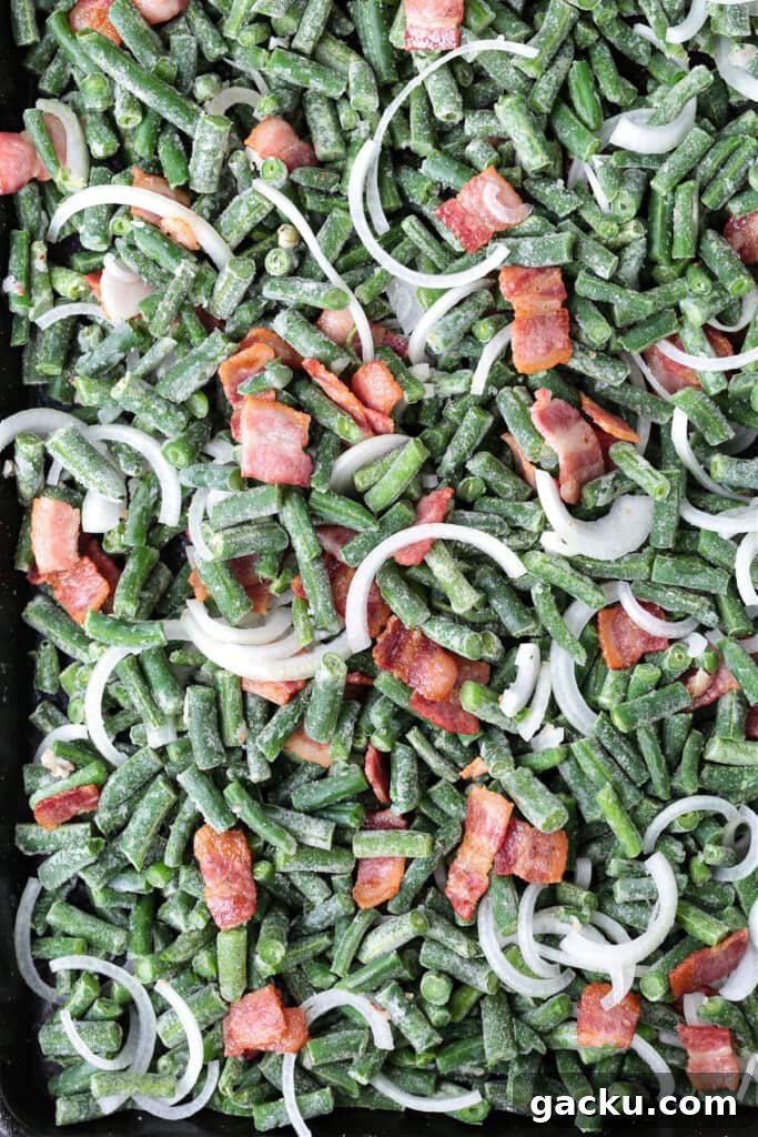 These Green Beans with Bacon are an easy to make, delicious vegetable side dish! Bacon and onions flavor the green beans while they cook! green beans, bacon and onions on a sheet pan