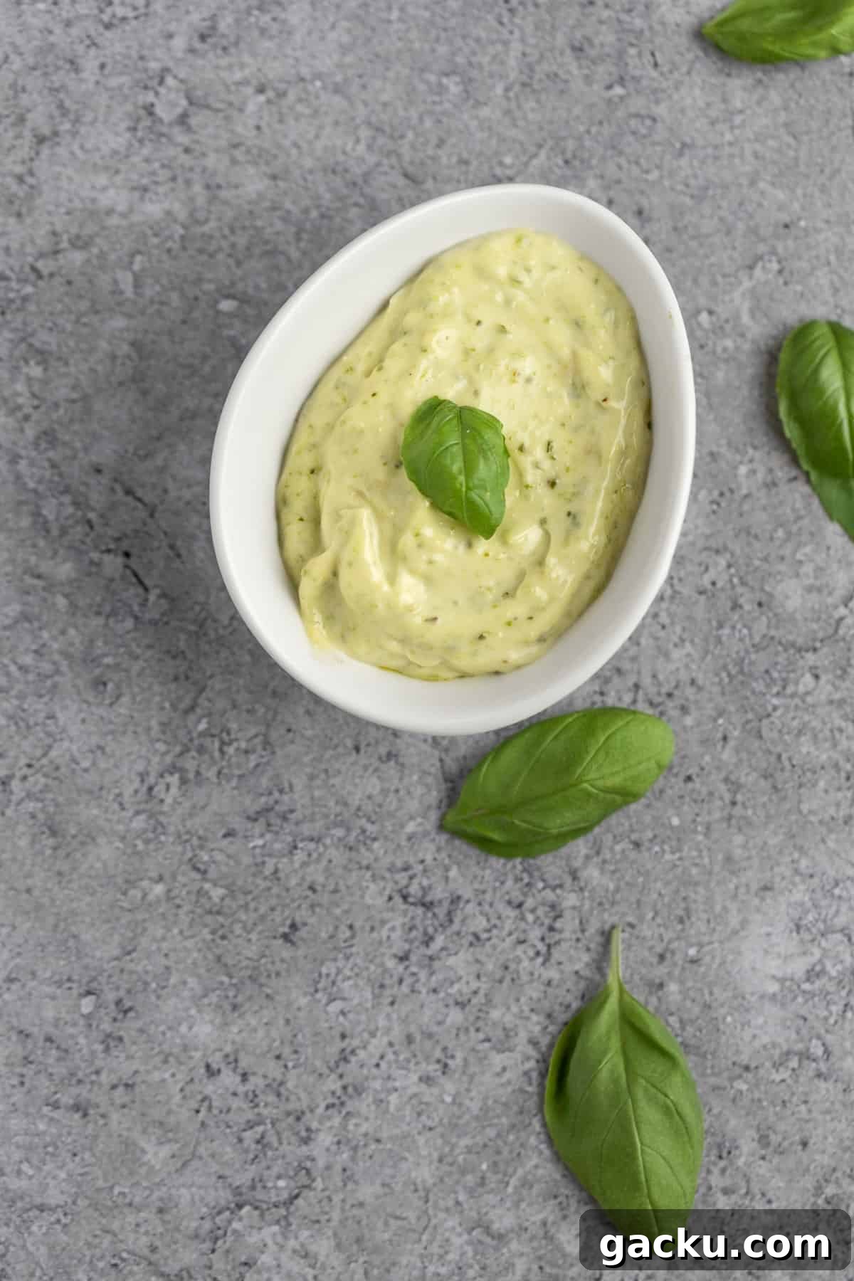 Creamy Pesto Aioli Recipe for Sandwiches & Dips 2 Pesto aioli garnished with fresh basil leaves, on a grey marble table.