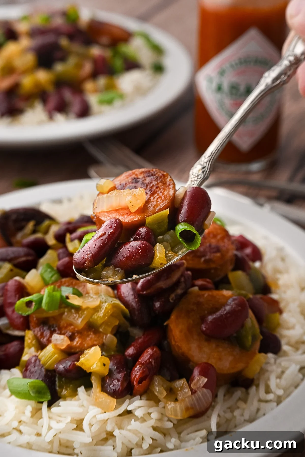 A spoon lifting a bite of red beans and sausage.