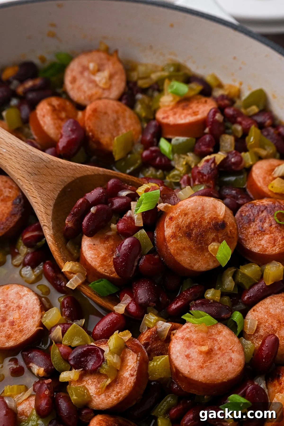 Red beans and sausage mixture simmering in a skillet to thicken the sauce without mashing the beans.