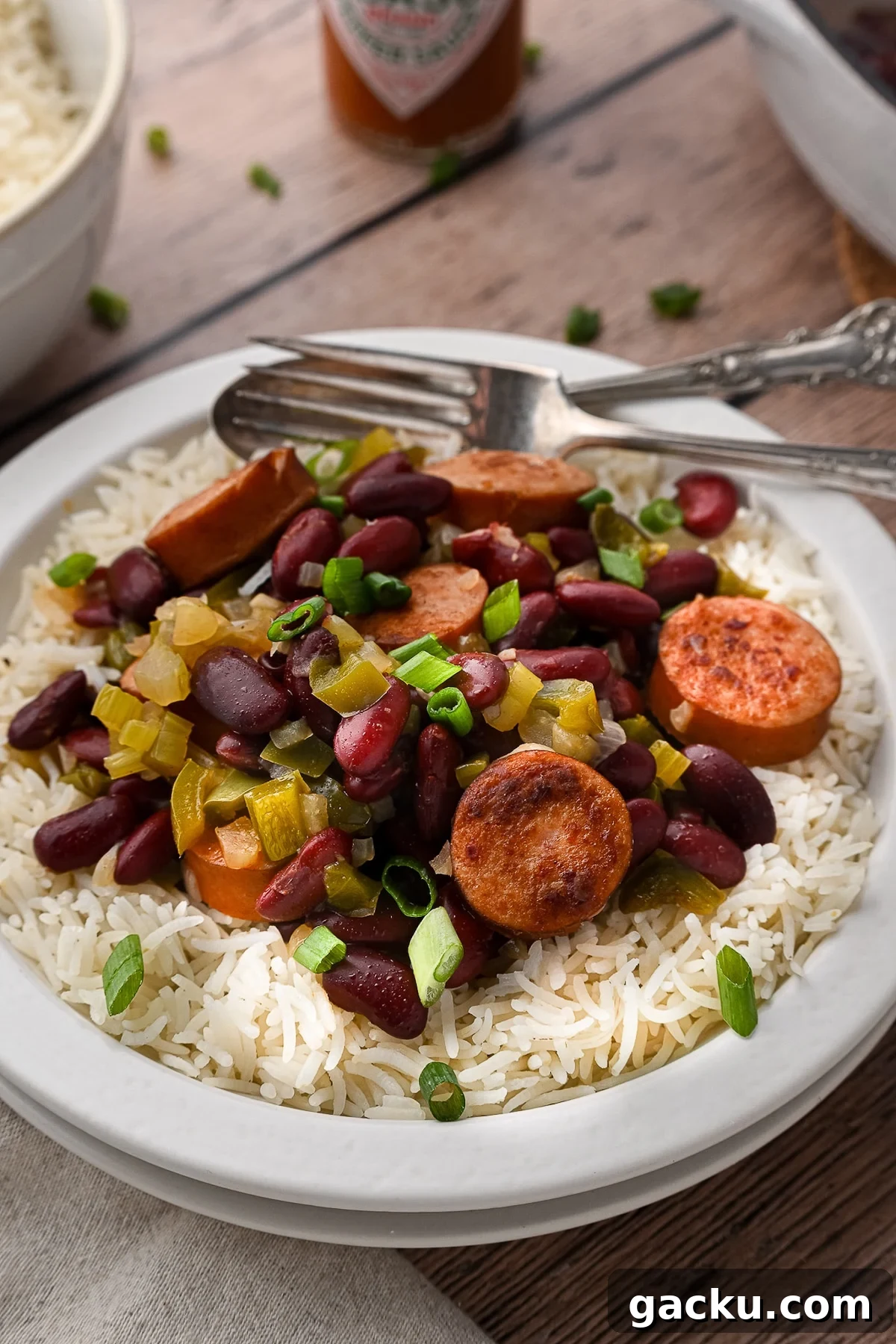 A plate of white rice topped with red beans and sausage.
