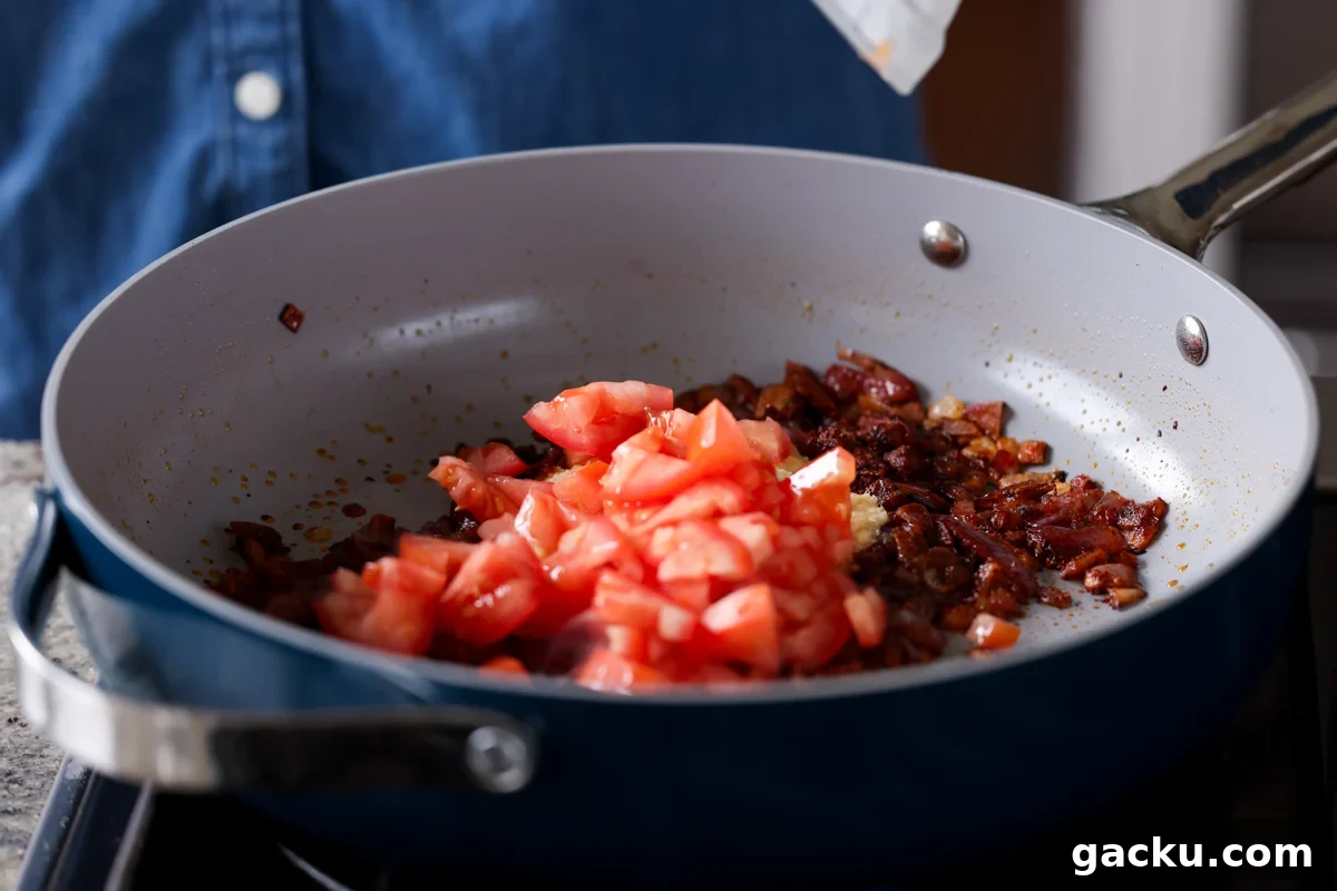 adding tomatoes to the pan