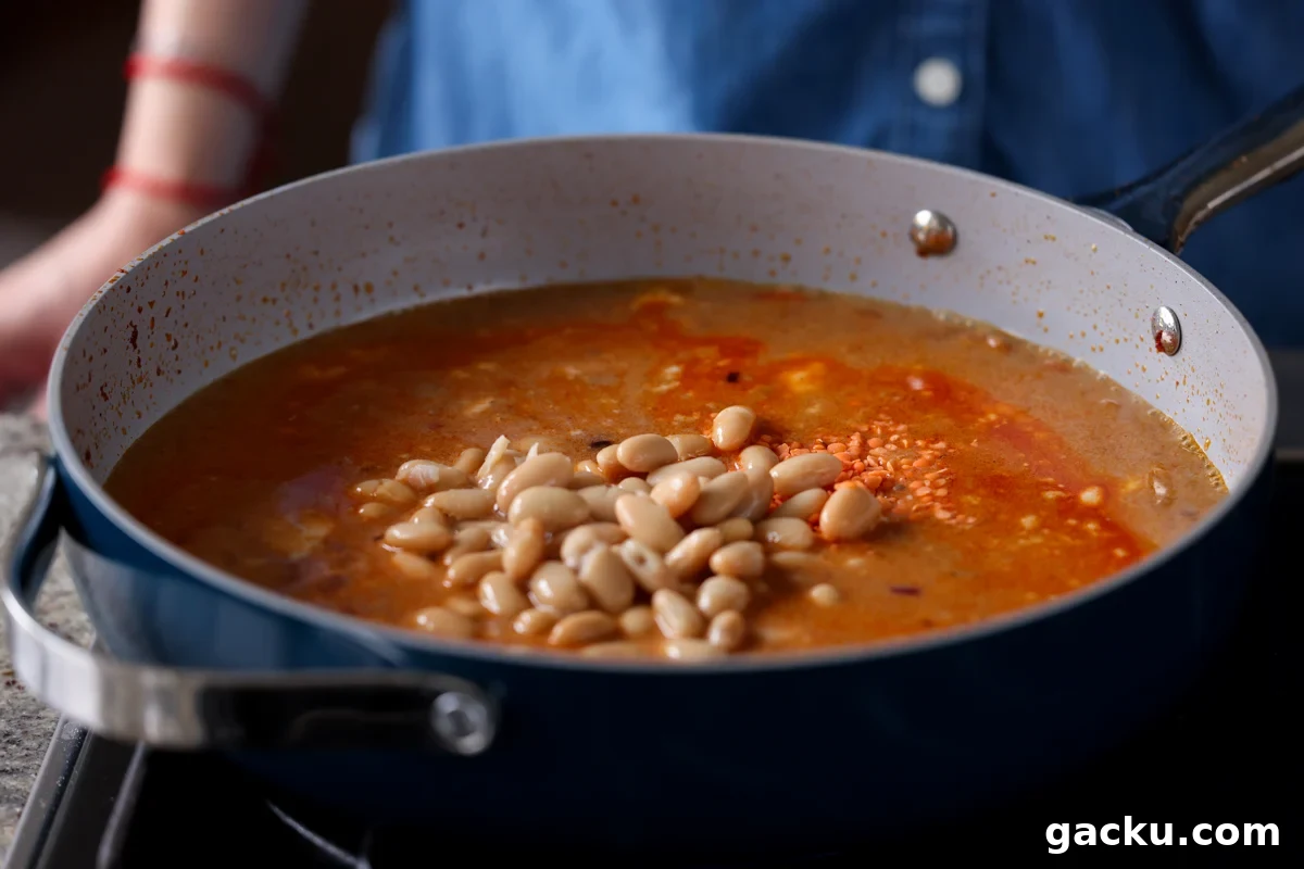 adding white beans to the pan