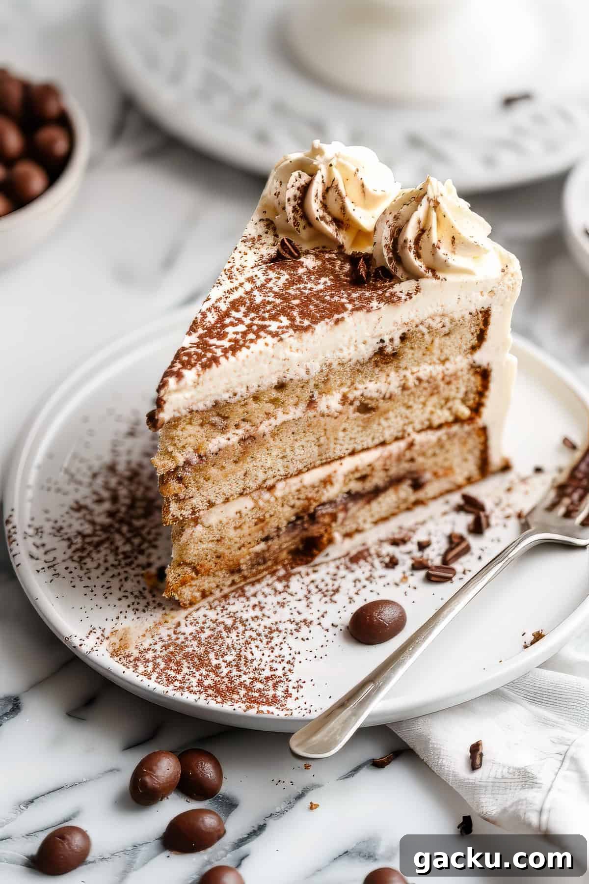 Classic Tiramisu Cake with Silky Mascarpone Frosting 5 A slice of tiramisu layer cake with a fork and some coffee beans.