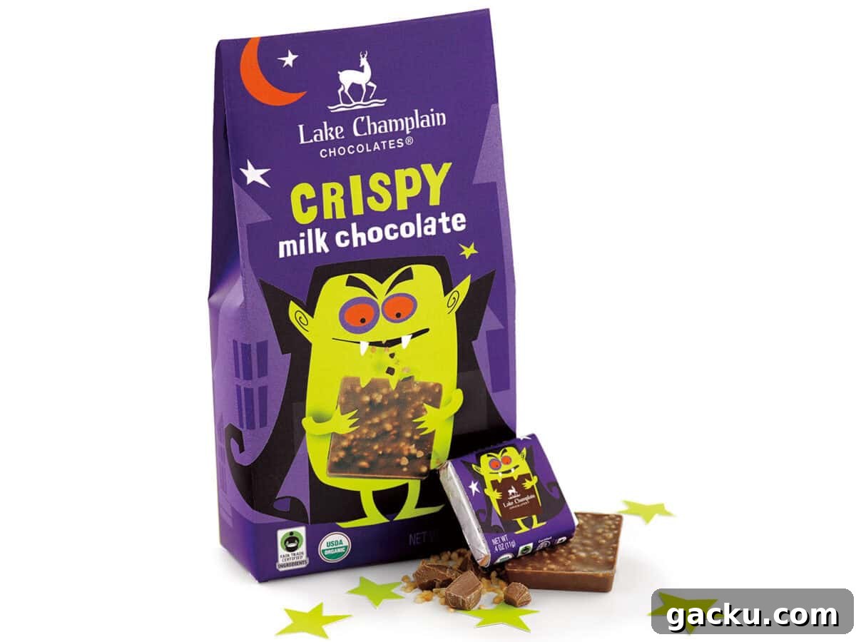 A purple bag of Lake Champlain Chocolates Crispy Milk Chocolate is shown, featuring a cartoon vampire illustration and a broken-off piece of chocolate on a white background with yellow stars.