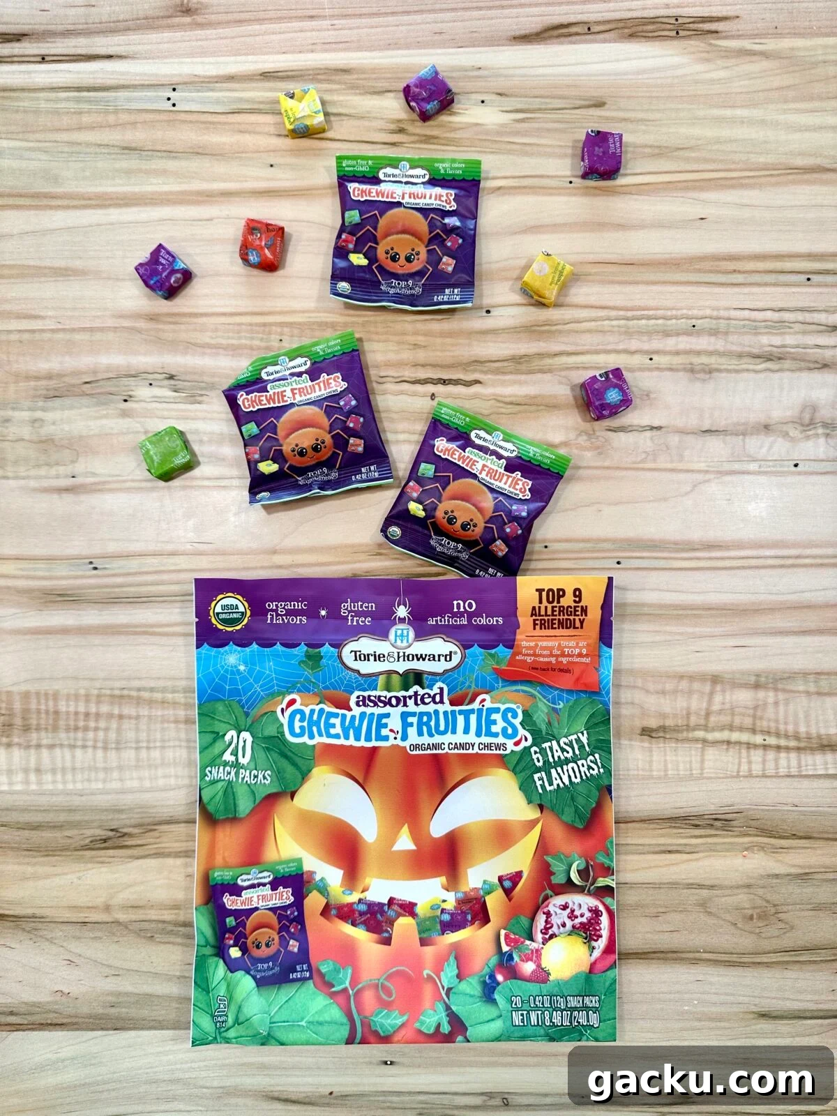 A box of assorted Torie & Howard Chewie Fruities is shown, with a large jack-o'-lantern on the front and smaller snack packs scattered around it.