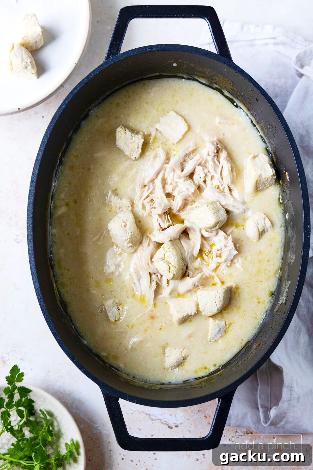 Shredded chicken and biscuit pieces added to slow cooker for chicken and dumplings.