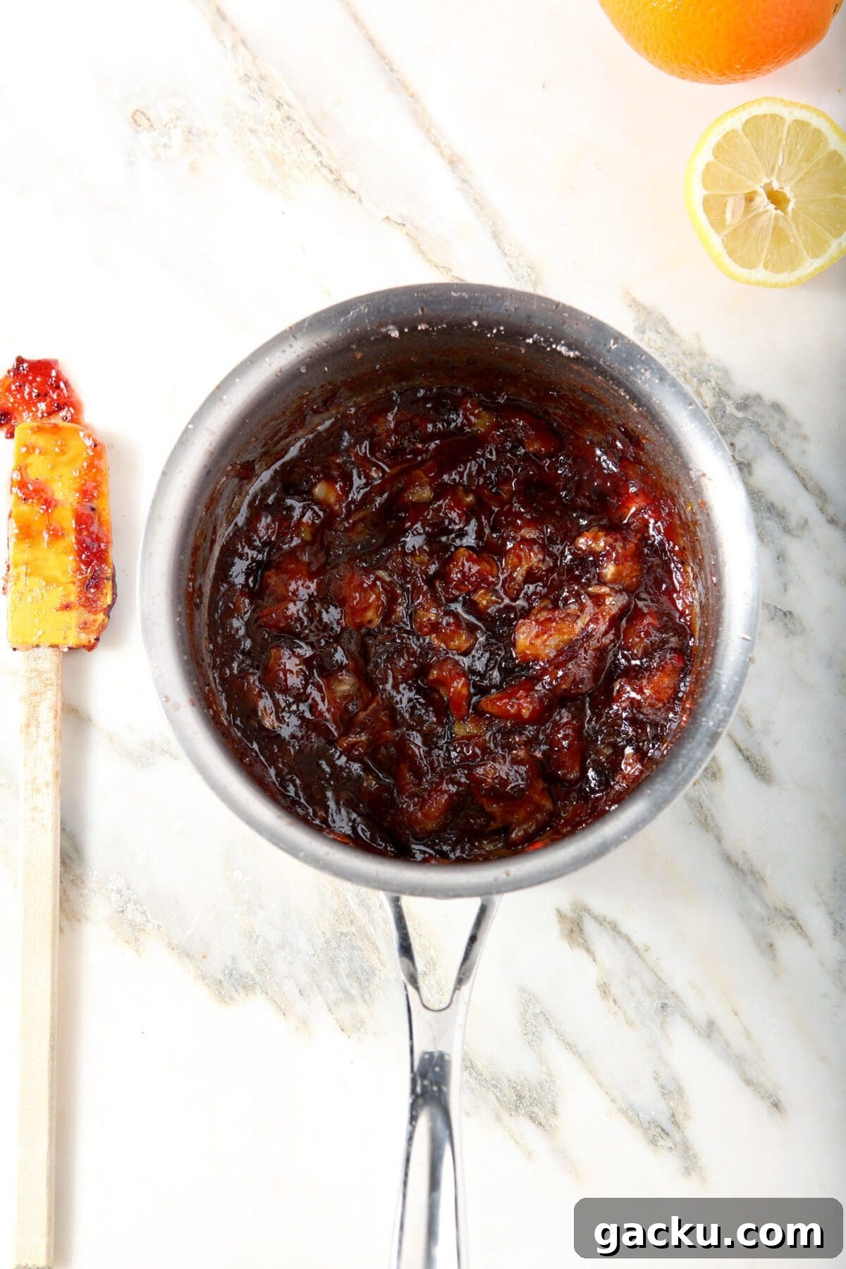 Orange cranberry compote in a saucepan on marble after cooking down