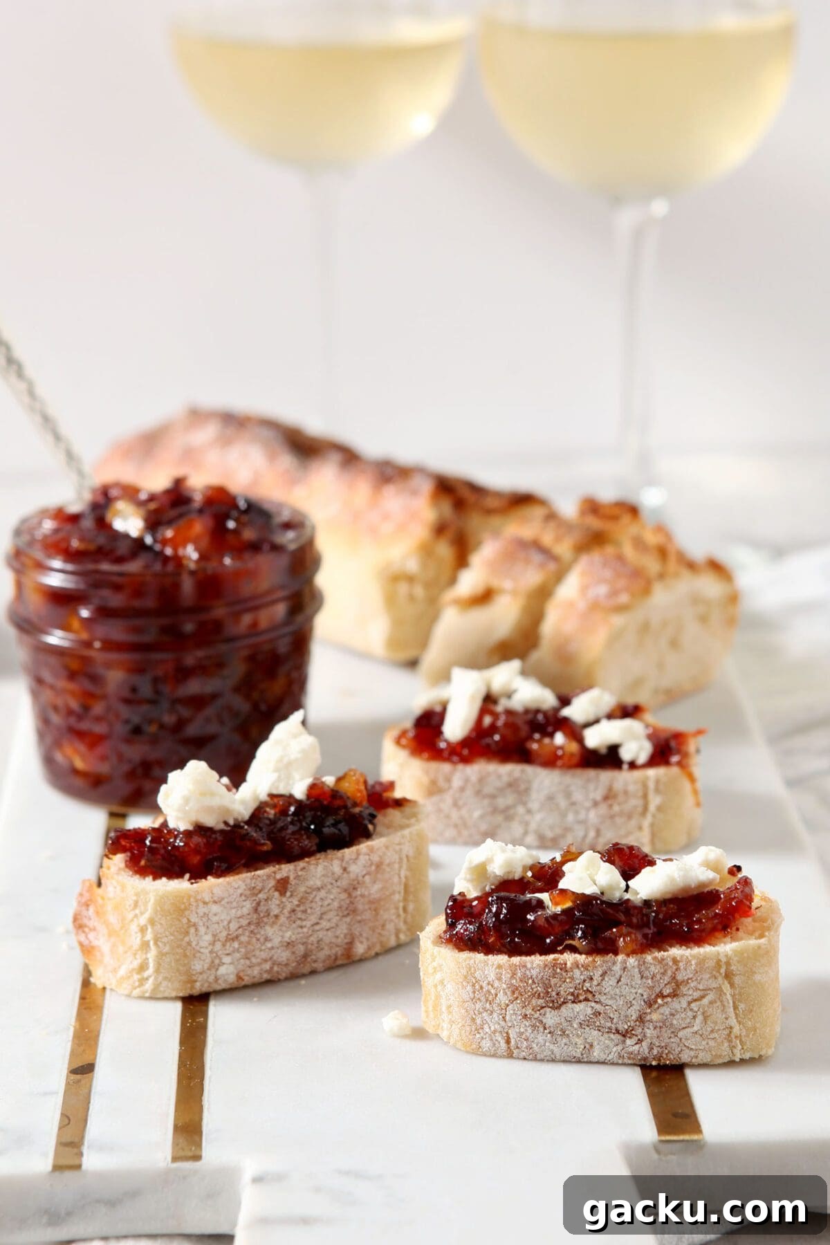 Close up of three slices of cranberry compote crostini in front of a jar of compote