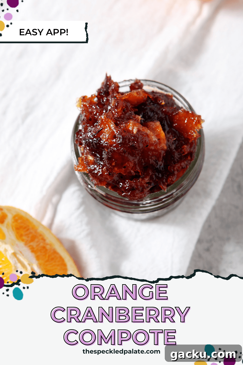 A jar of cranberry compote on a white linen towel next to orange slices with the text orange cranberry compote