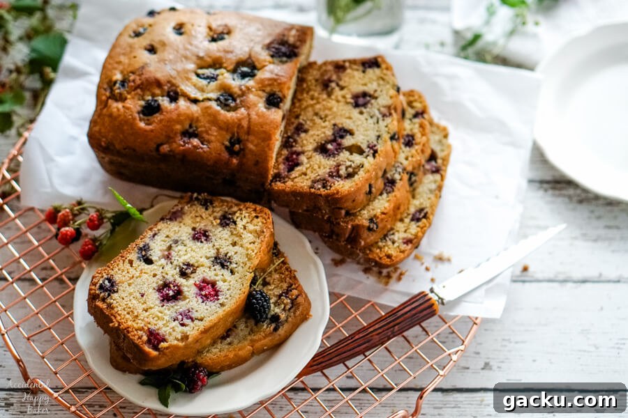 Moist Homemade Blackberry Bread Recipe for Summer Baking 2 Two slices of blackberry bread on a white plate next to a loaf of sliced blackberry bread.