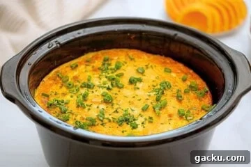 Crockpot with cooked breakfast casserole made with hashbrowns, ham, eggs, cheeses, peppers, and onions.