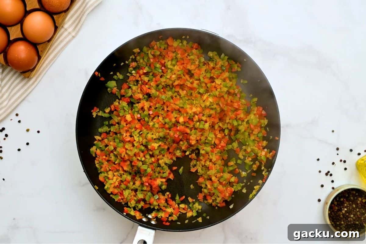 Peppers and onions in large skillet after being sauteed for slow cooker breakfast casserole.