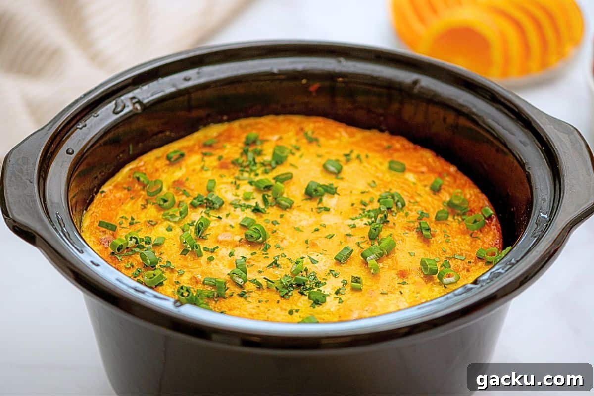 Crockpot with cooked breakfast casserole made with hashbrowns, ham, eggs, cheeses, peppers, and onions.