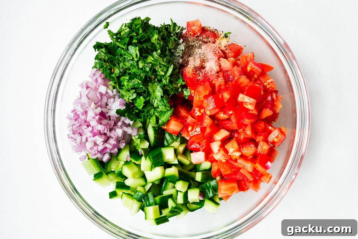 Cubed israeli salad ingredients in a mixing bowl.