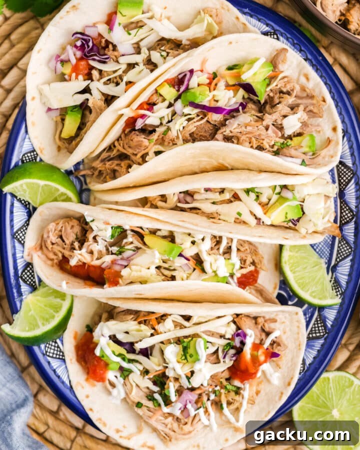A plate with pulled pork tacos with lime garnish.