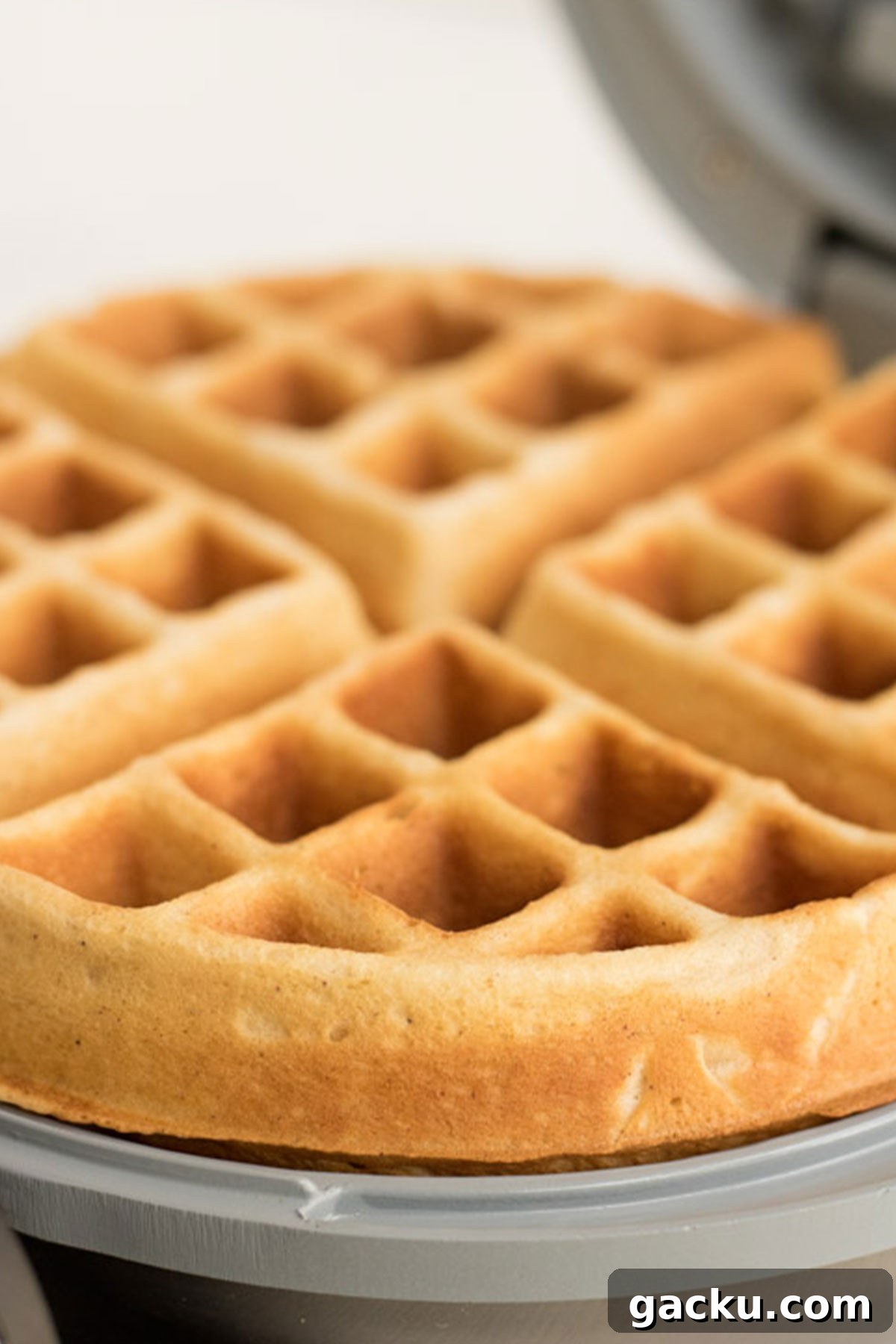 Eggnog waffle being cooked in a waffle iron. 