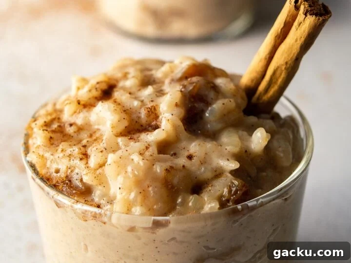 A glass jar of rice pudding with a cinnamon stick stuck in it.