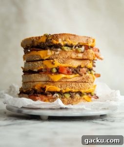 3 sandwich halves stacked on each other on small marble board