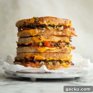 3 sandwich halves stacked on each other on small marble board