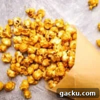 Homemade caramel corn spilling out of a parchment cone.